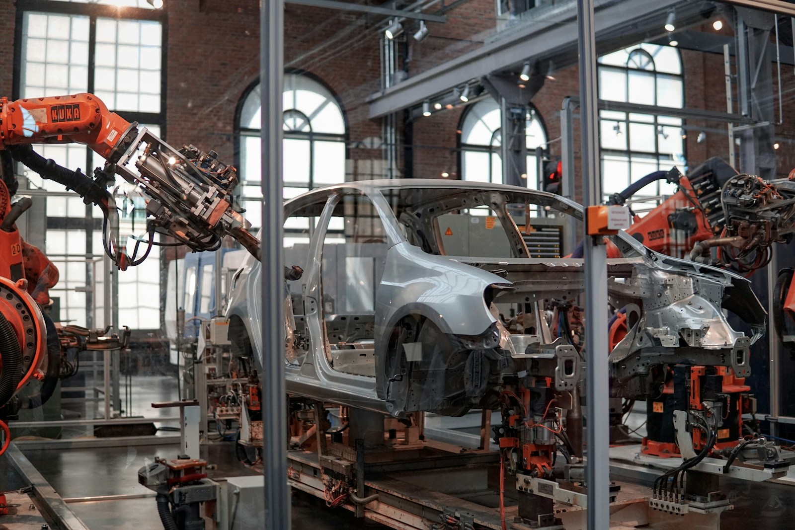 Línea de ensamble automotriz con brazos robóticos KUKA, chasis en proceso y celdas de soldadura — manufactura industrial moderna