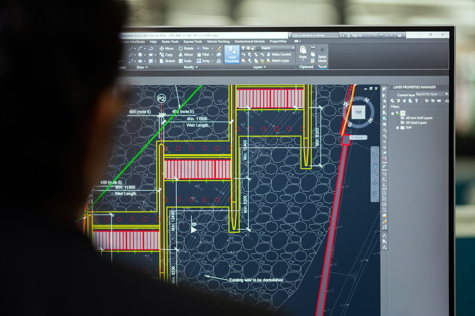 Ingeniero revisando planos hidráulicos sobre pantalla AutoCAD para diseño de planta industrial
