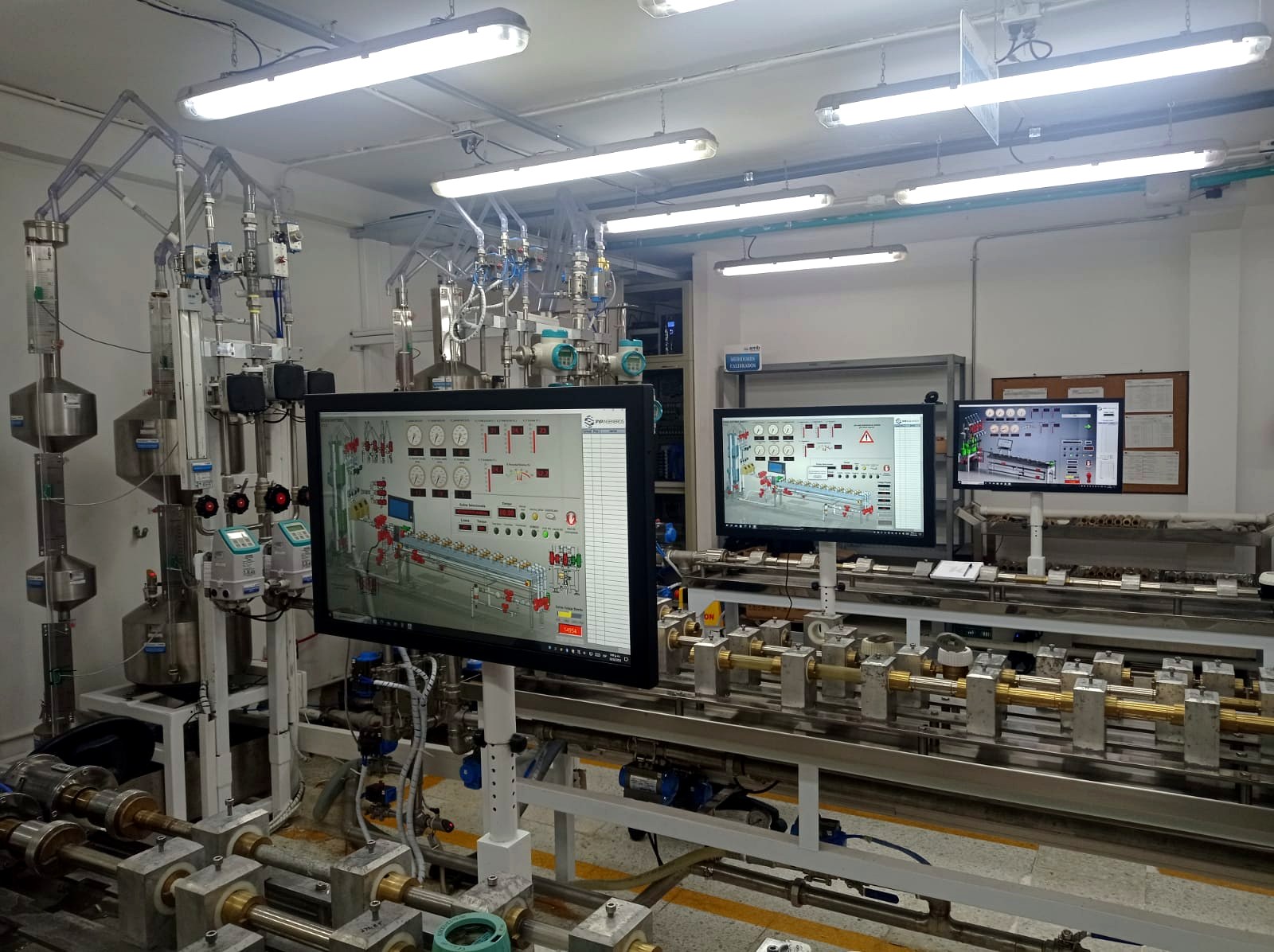Laboratorio P&P con tres monitores SCADA SOFTMED operando en simultáneo sobre un banco de calibración de medidores